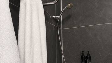 Un baño con ducha, perchero y estante con artículos de aseo.