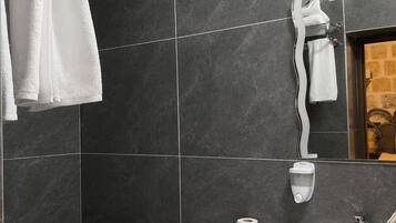 A bathroom with dark tiles, a white toilet, a sink, and a towel rack.