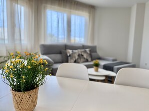 Ein Wohnzimmer mit einer Couch, einem Couchtisch und einem Blumentopf mit gelben Blüten.