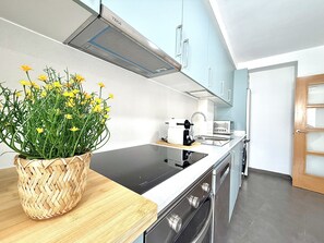 Eine moderne Küche mit Einbauherd, Spüle und Toaster. Auf der Arbeitsfläche steht ein gewebter Korb mit gelben Blumen.