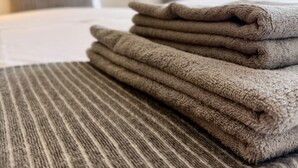 A neatly made bed with a striped blanket and folded towels. - Dragos Suites 204 (Arrecife)