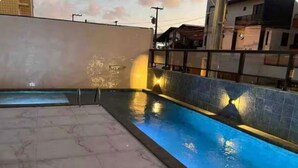 Una piscina con bordo piastrellato, un elemento d'acqua e vista sul tramonto.