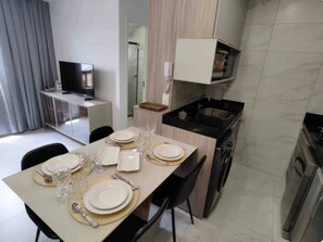 A modern kitchen with a dining area, a TV, and a microwave. - Hermano 504 · Modern apartment 300 meters from Bessa beach (João Pessoa)
