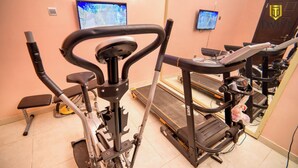 Un gimnasio con equipo de ejercicio, incluyendo una cinta de correr y bicicletas estáticas.