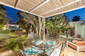 A glass-top table with chairs and cushions, surrounded by plants and a covered area. - Seaside Gallipoli Modern Villa for 8 (Gallipoli)