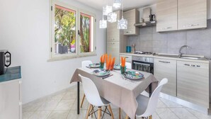 Een moderne keuken met een eethoek, een raam met uitzicht op groen, en een gedekte tafel voor twee.