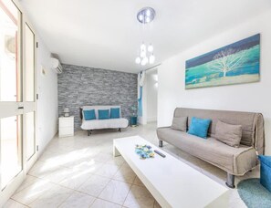 Ein modernes Wohnzimmer mit Steinwand, einem weißen Sofa, einem grauen Sofa, einem weißen Couchtisch und einem Bild an der Wand.
