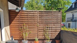 A covered patio area with a wooden fence, potted plants, and outdoor furniture. - Vacation apartment on the edge of the Sauerland and the border of the Ruhr area (Wickede (Ruhr))