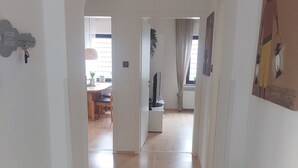 A hallway with an arched doorway leading to a dining area with a table and chairs, a television, and a radiator on the wall. - Vacation apartment on the edge of the Sauerland and the border of the Ruhr area (Wickede (Ruhr))