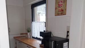 A kitchen with white cabinets, a wooden countertop, a coffee maker, and a vintage cupcake poster. - Vacation apartment on the edge of the Sauerland and the border of the Ruhr area (Wickede (Ruhr))
