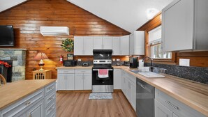 Una cucina con pareti in legno, un camino in pietra e un piano cottura moderno.