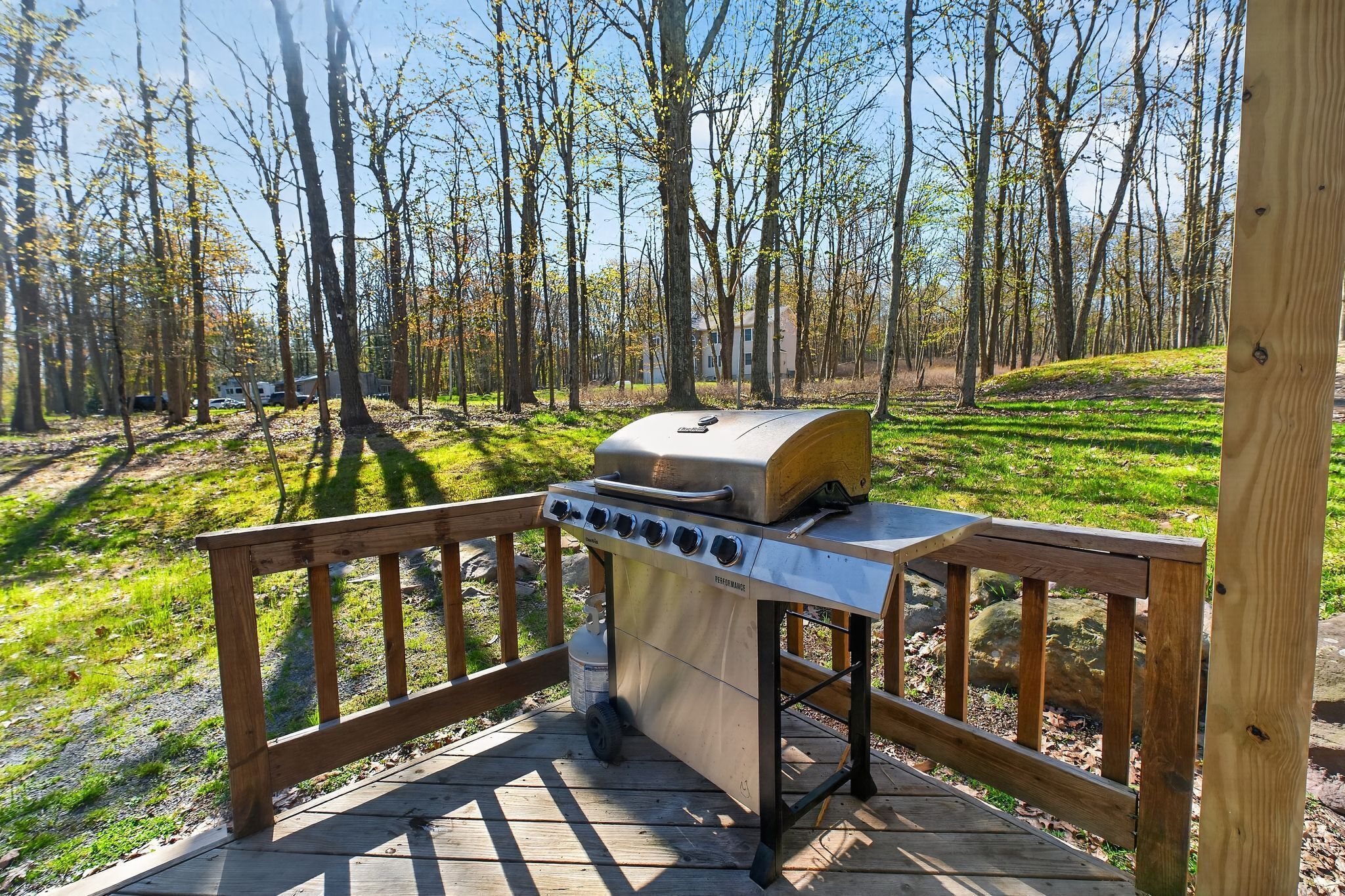 Ein Grill auf einer Holzterrasse mit Blick auf einen Wald.