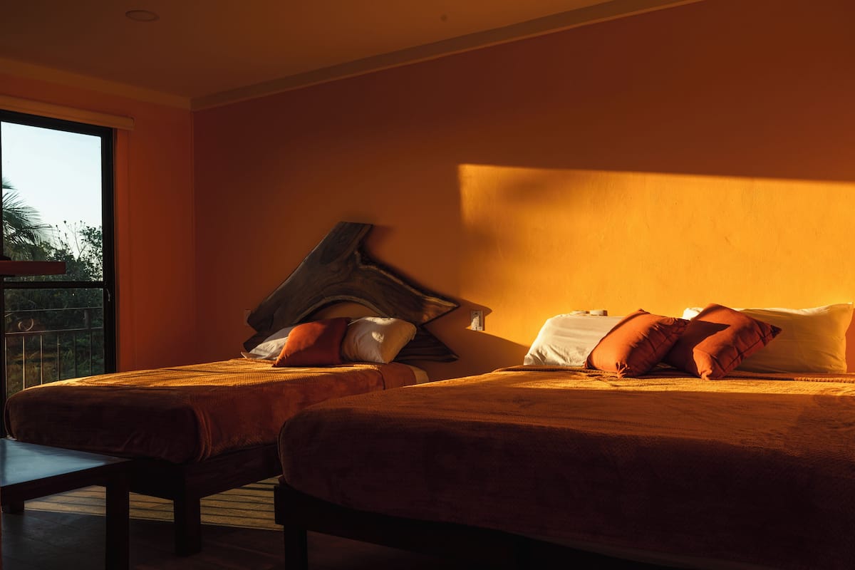 Une chambre d’hôtel avec deux lits, une grande fenêtre et un balcon.