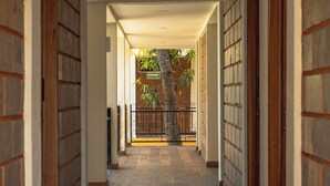 A corridor with tiled flooring, wooden doors, and a view of a tree outside.