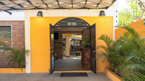 A building entrance with a yellow wall, a brick section, and a metal gate.