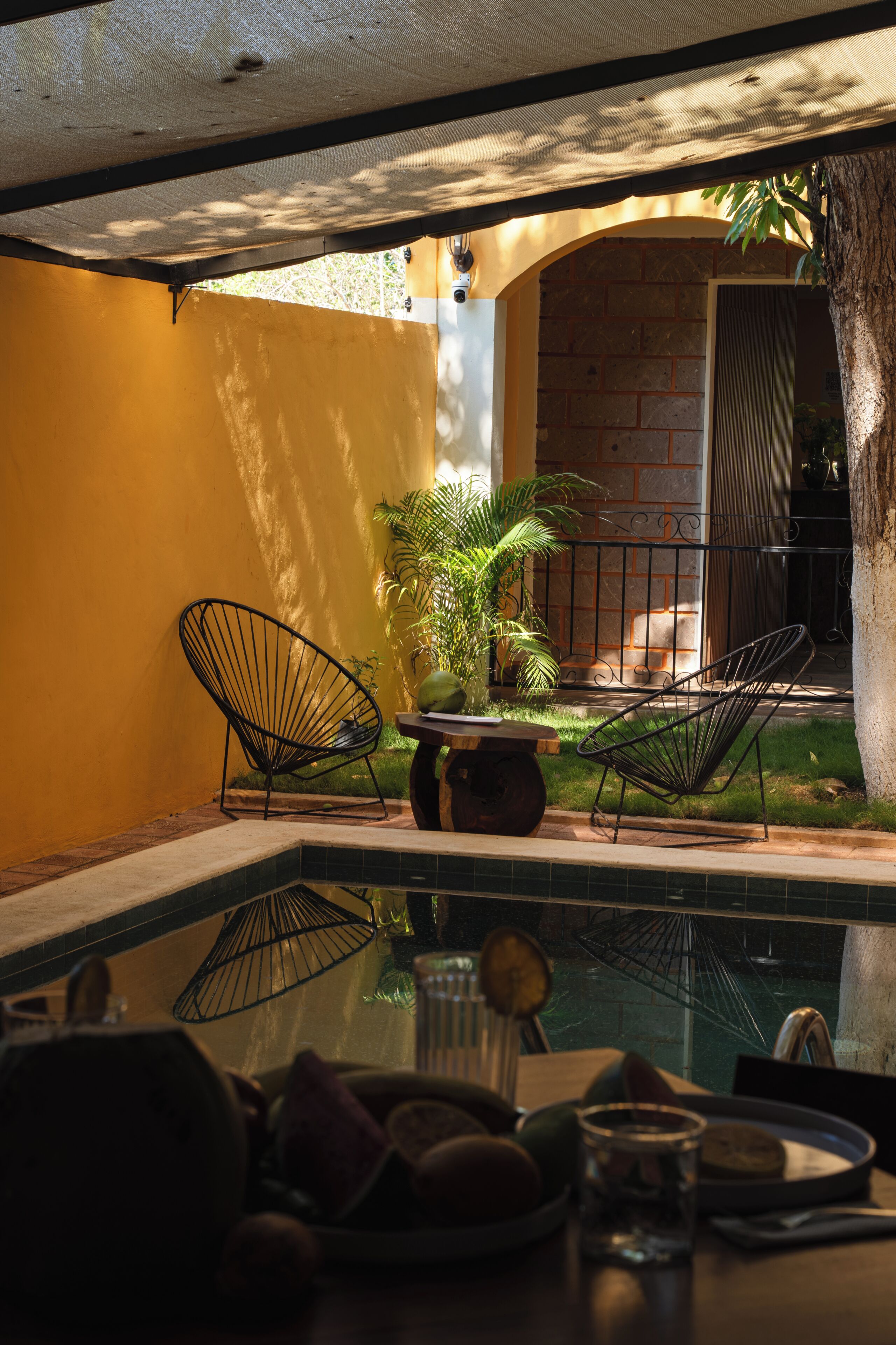 Un área de estar al aire libre con dos sillas, una mesa y una piscina pequeña.