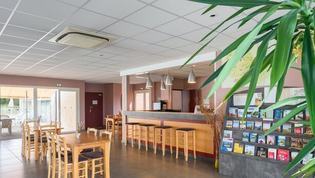 A reception area with a counter, seating, and a book display. - Countryside Stay Near Albi Vineyard (Rivieres)