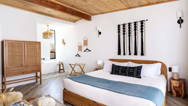 Een slaapkamer met een groot bed, houten hoofdeinde en uitzicht op de omgeving.