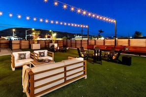 An outdoor seating area with wooden furniture, string lights, and a view of the mountains.