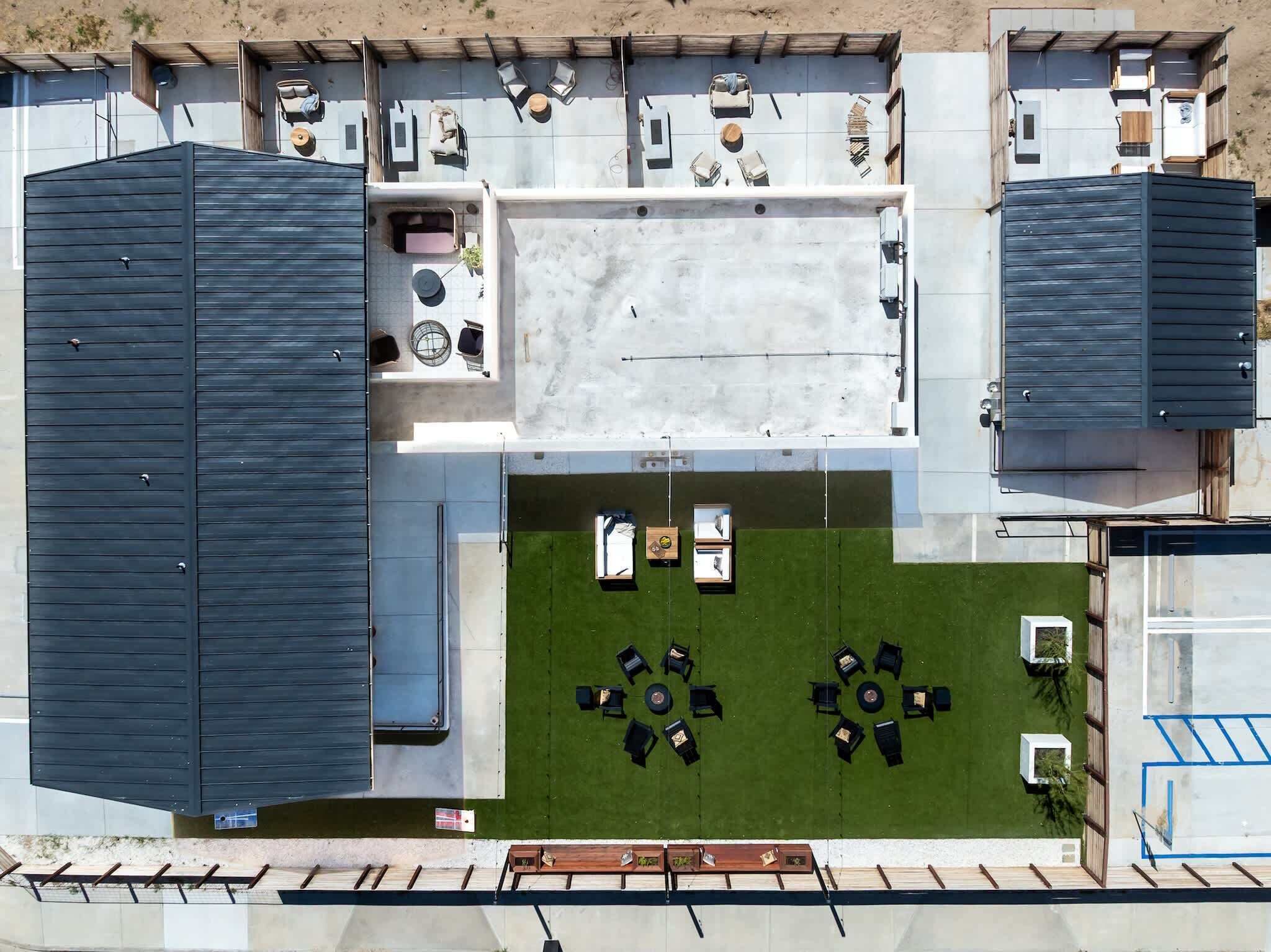 An aerial view of a modern building with multiple rooms, a central courtyard with seating, and a covered outdoor area.