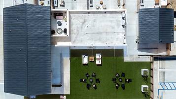 An aerial view of a modern building with multiple rooms, a central courtyard with seating, and a covered outdoor area.