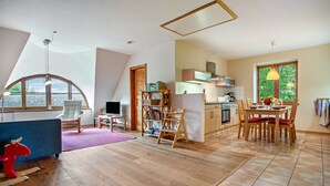 A spacious room with a dining area, kitchen, and a large window providing natural light. - Apartment "Kastanie" with Private Outdoor Terrace in the Garden (Putbus)