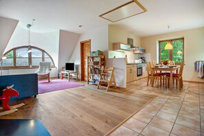 A spacious room with a dining area, kitchen, and a large window providing natural light. - Apartment "Kastanie" with Private Outdoor Terrace in the Garden (Putbus)