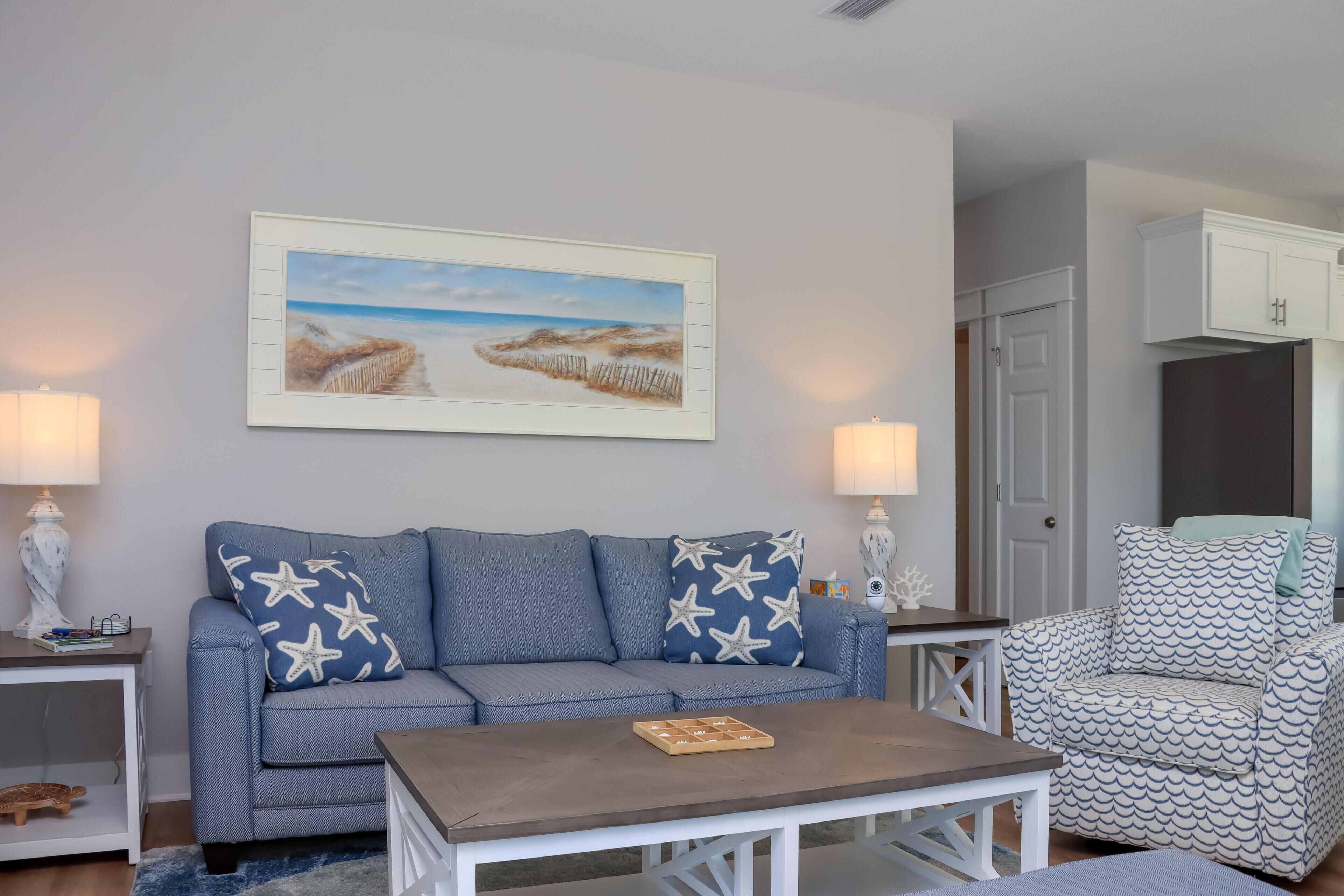A living room with a sofa, armchair, coffee table, and a painting on the wall.