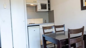 A compact kitchen with a microwave, a small refrigerator, and a dining table with chairs. - Apartment in Grasse With Swimming Pool (Grasse)