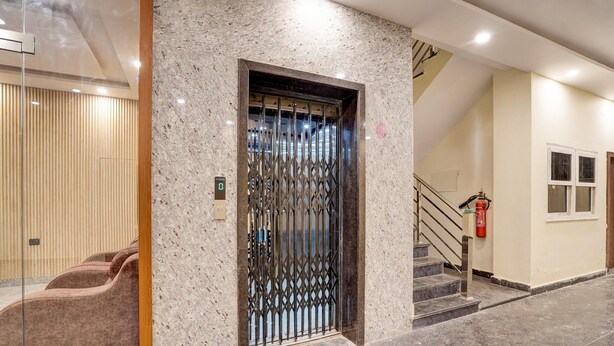 A lobby with a marble wall, a metal gate, a staircase, and a fire extinguisher. - Collection O Zero Mile Patna (Patna)