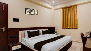 A hotel room with a bed, a desk, a phone, a plant, and artwork on the wall. - Collection O Zero Mile Patna (Patna)