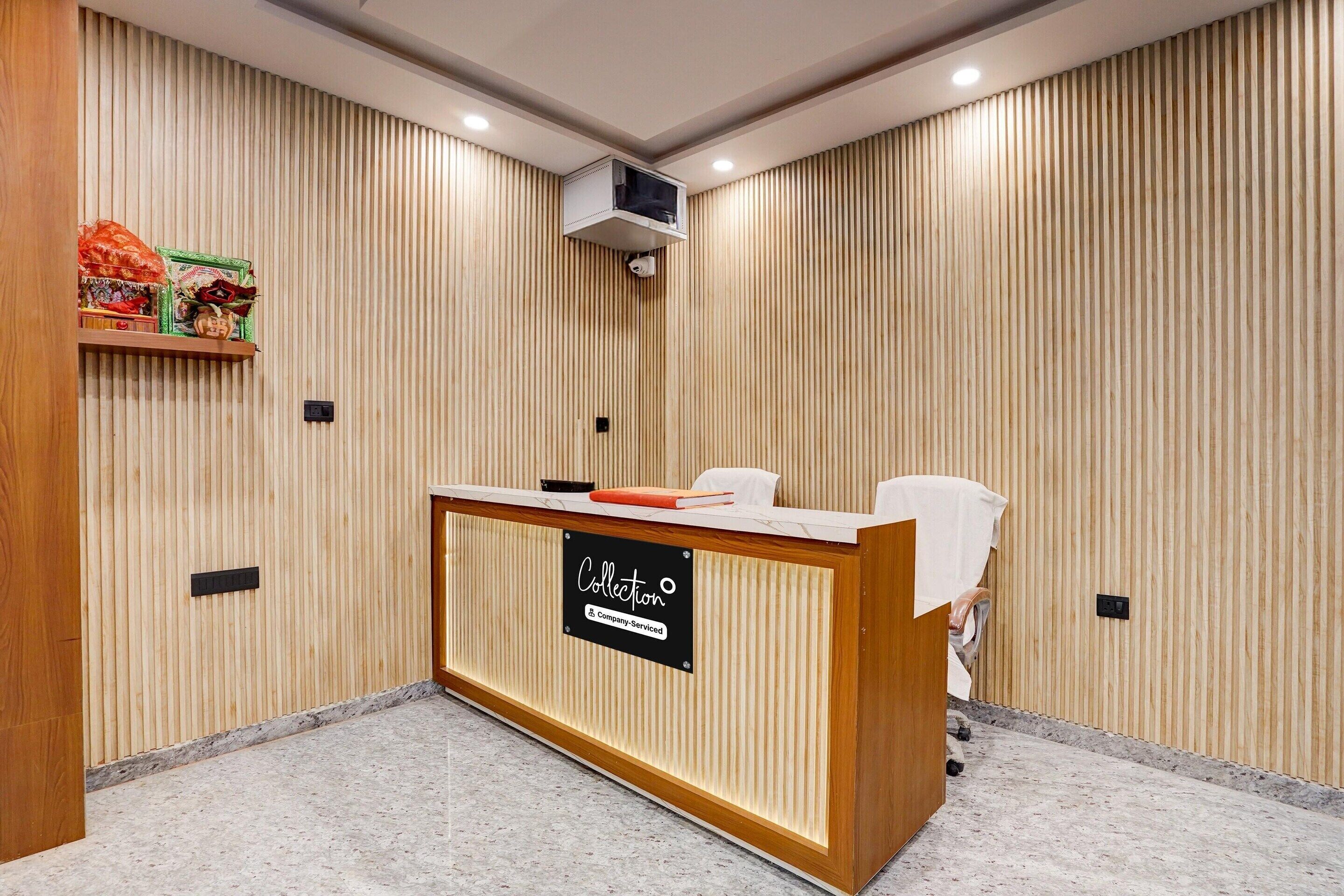 A reception desk with a sign, a wooden wall with vertical slats, and a ceiling-mounted air conditioning unit.
