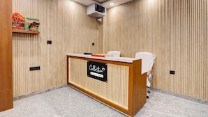 A reception desk with a sign, a wooden wall with vertical slats, and a ceiling-mounted air conditioning unit. - Collection O Zero Mile Patna (Patna)
