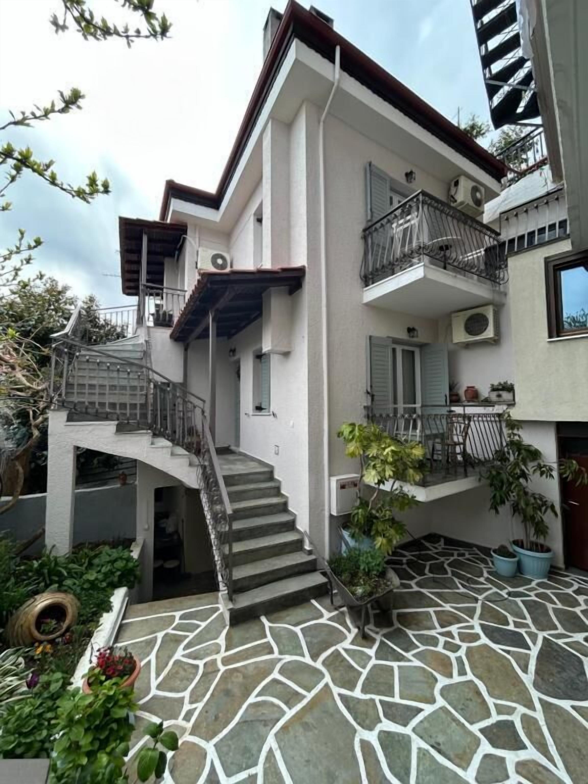 A two-story building with a stone-tiled courtyard, a staircase leading to the upper floor, and balconies with railings.
