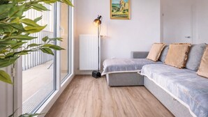 Uma sala de estar moderna com um sofá cinzento, um radiador, um abajur e um quadro na parede.