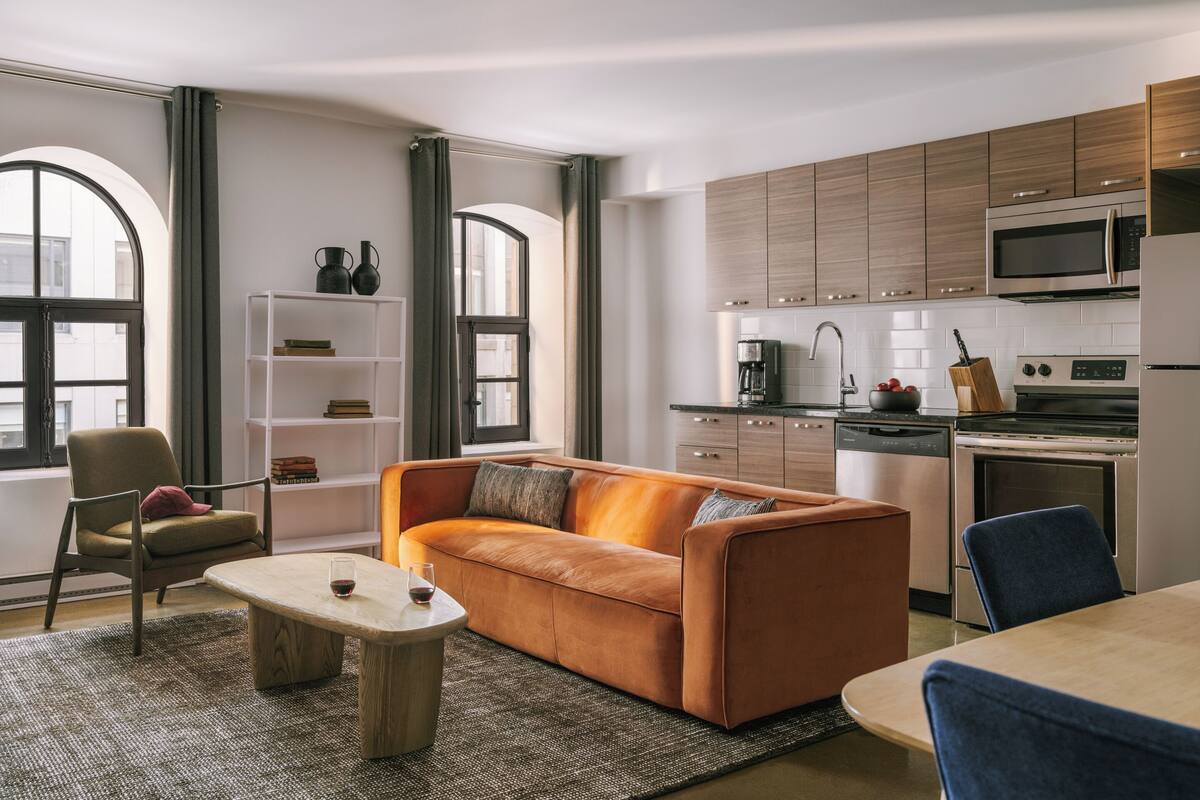 A modern kitchen with built-in appliances, a sofa, and a dining area.