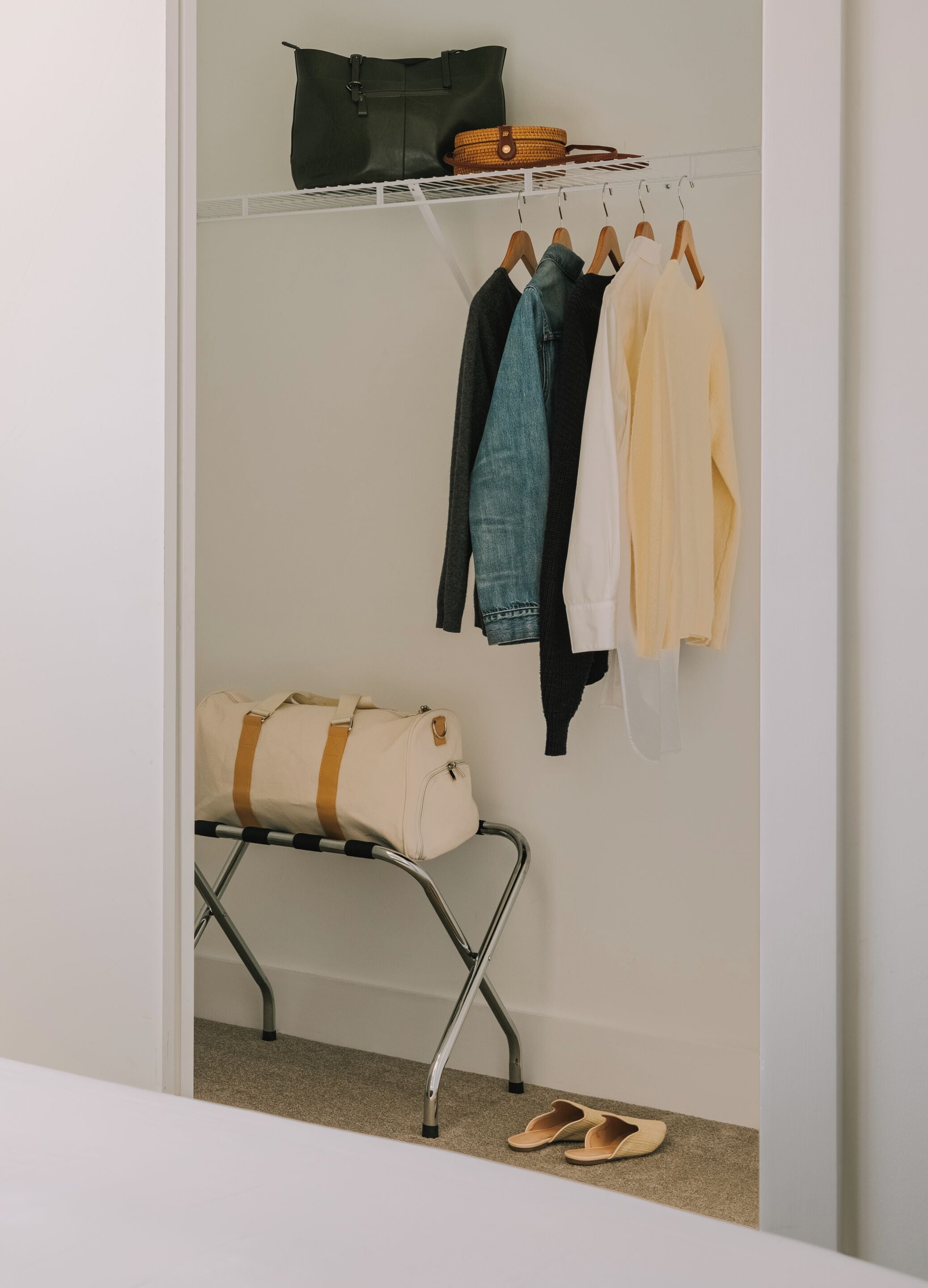 A closet with hanging clothes, a folded bag, and a pair of shoes on the floor.