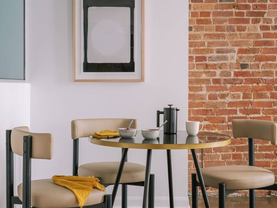 Une table ronde avec des chaises, une cafetière, des bols et une tasse.