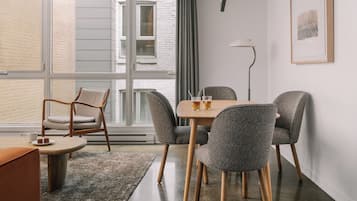 Zona pranzo moderna con tavolo, sedie e vista su un edificio in mattoni attraverso ampie finestre.