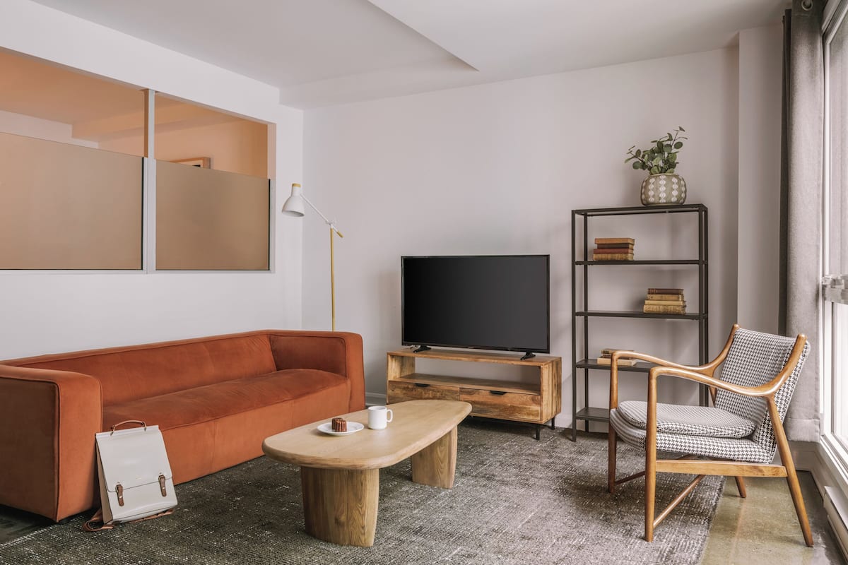 A living room with a sofa, a coffee table, a television, a chair, a bookshelf, and a window.