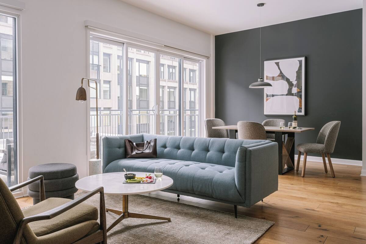 A modern living room with a sofa, chairs, a round coffee table, and a dining area with a table and chairs.
