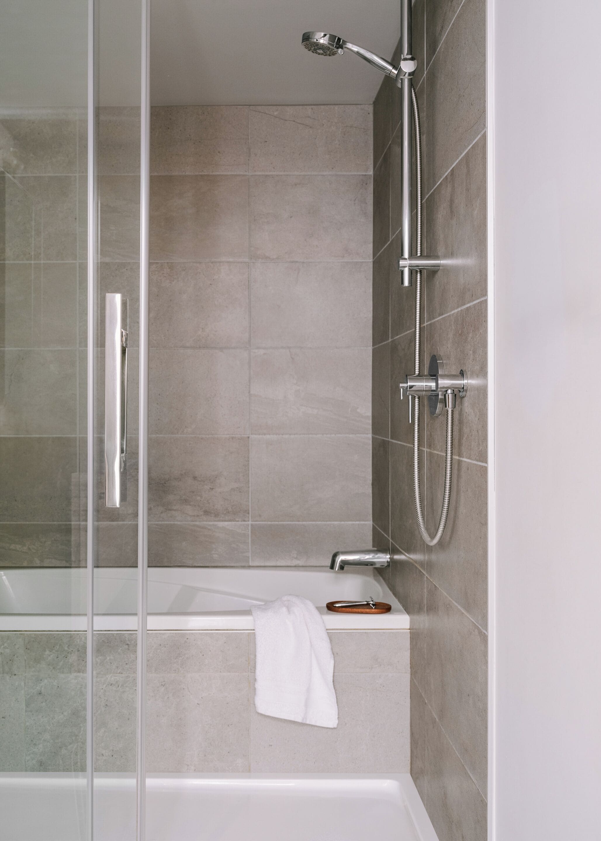 Ein modernes Badezimmer mit Duschkabine aus Glas, einer weißen Badewanne und einer Handbrause.