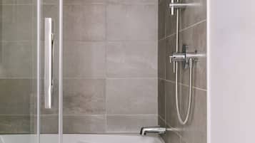 Ein modernes Badezimmer mit Duschkabine aus Glas, einer weißen Badewanne und einer Handbrause.