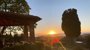 Una pérgola con vistas a la puesta de sol sobre un paisaje montañoso.