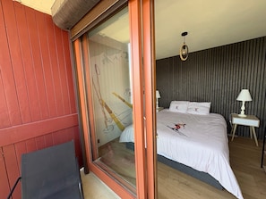 Een slaapkamer met een bed, een nachtkastje, een lamp en een schuifdeur met een afbeelding van bamboe.