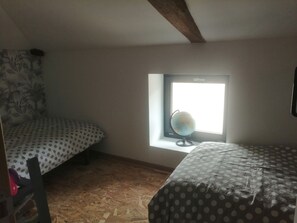 Une chambre avec un lit superposé, une fenêtre ornée d’un globe terrestre et un mur décoré de motifs.
