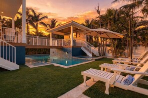 A pool area with a covered deck, lounge chairs, and a staircase leading to an upper level. - Slice of Paradise by Duncan Real Estate (Holmes Beach)