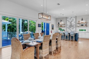 A spacious dining area with wicker chairs, a wooden table, and a view of the outdoors. - Slice of Paradise by Duncan Real Estate (Holmes Beach)
