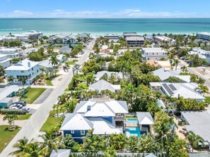 A coastal residential area with houses, a swimming pool, and a view of the ocean. - Slice of Paradise by Duncan Real Estate (Holmes Beach)
