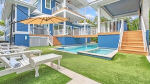 Une maison à deux étages dotée d’une piscine, d’un espace extérieur aménagé pour se détendre et d’un patio couvert.